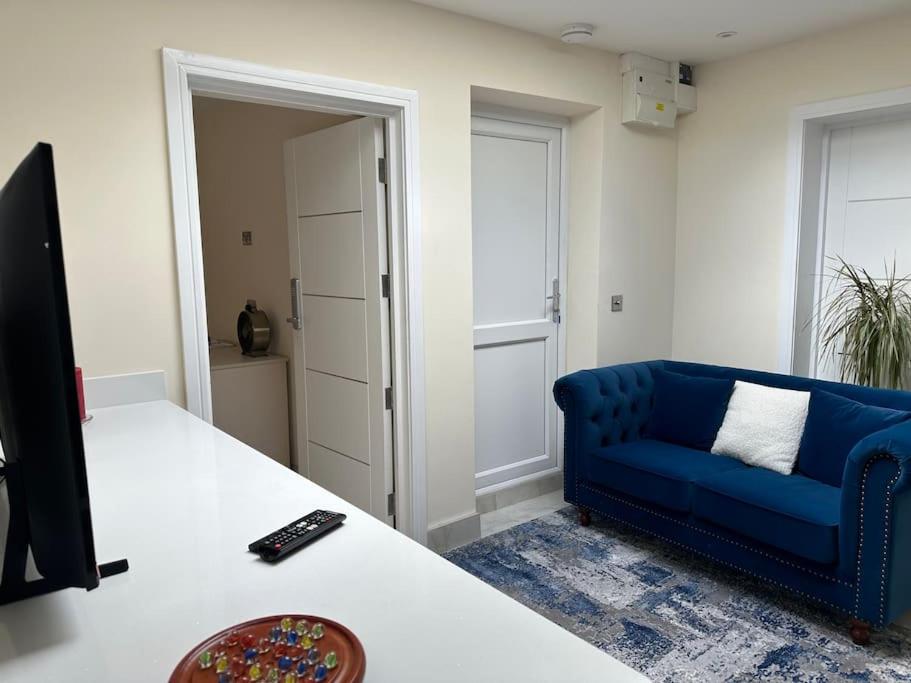 een woonkamer met een blauwe bank en een televisie bij CozyCorner - 2 Bed in Egham Heathrow Windsor in Egham