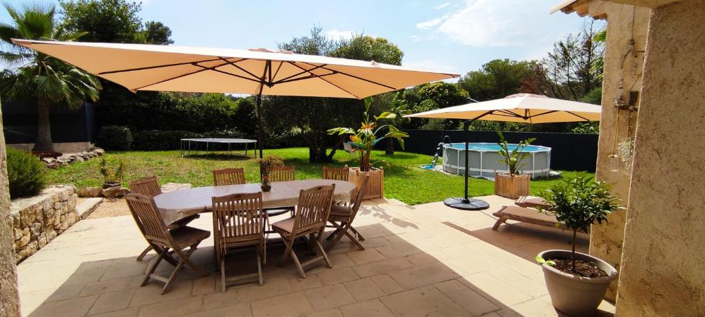 un patio avec une table, des chaises et un parasol dans l'établissement VILLA PROVENÇALE entre ANTIBES et CANNES, à Vallauris