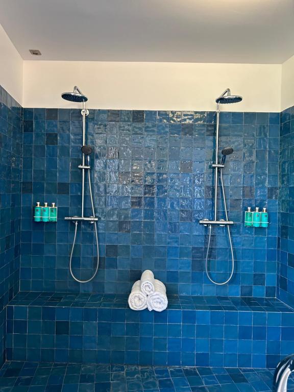 a blue tiled bathroom with two shower heads and towels at Maï Homes - La Villa Bompard in Marseille