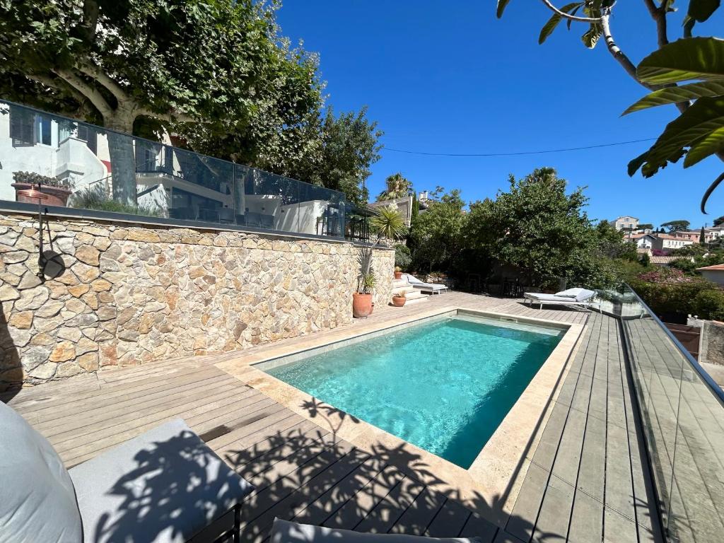 a swimming pool with a wooden deck and a house at Maï Homes - La Villa Bompard in Marseille