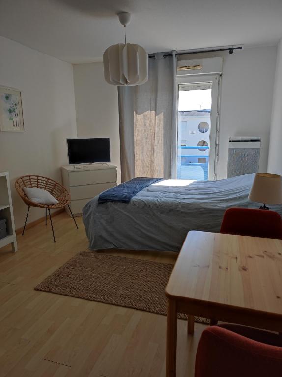 une chambre avec un lit, une table et une fenêtre dans l'établissement Les Jasmins d'Aytré, à Aytré