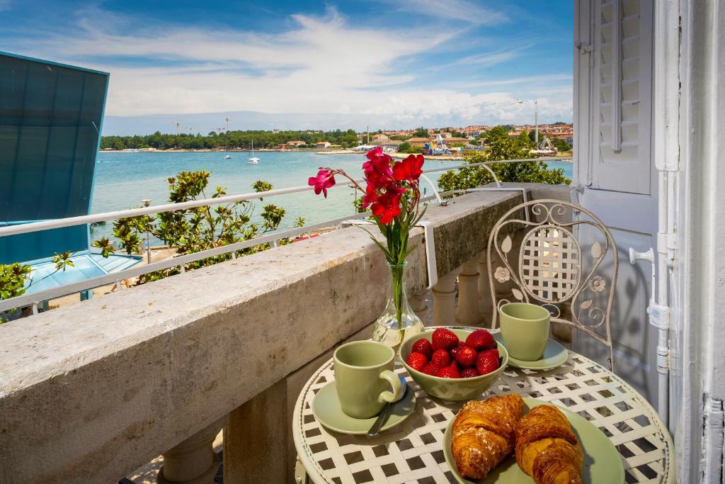 Una mesa con croissants y un bol de fruta en un balcón. en Romeo and Juliet Apartment with Balcony and Sea View, en Poreč