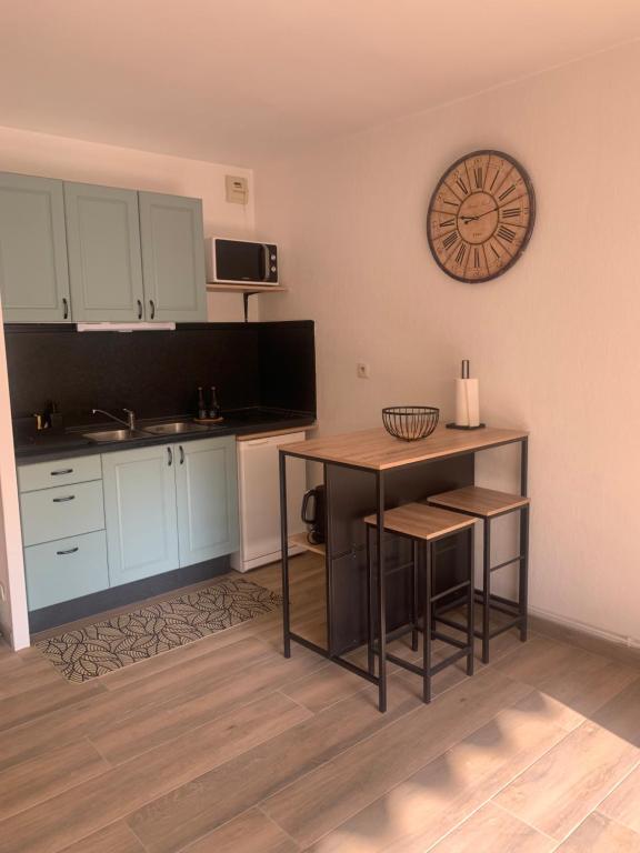 une cuisine avec des placards blancs, une table et une horloge dans l'établissement Petit cocon dans le 8 ème, à Marseille