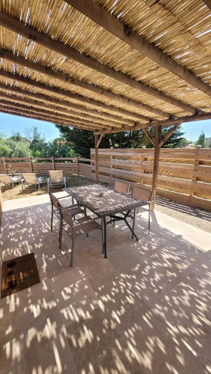 un patio avec une table et des chaises sous un toit en bois dans l'établissement Appart dans villa, terrasse et jardin, à Lorgues