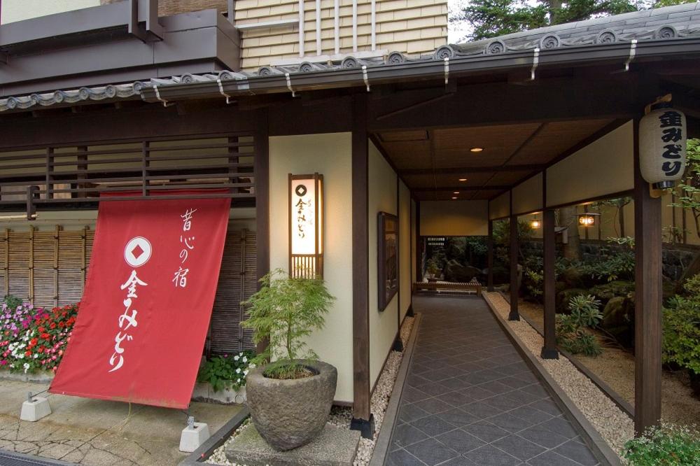 un edificio con una señal roja en el costado. en Kanemidori, en Kusatsu