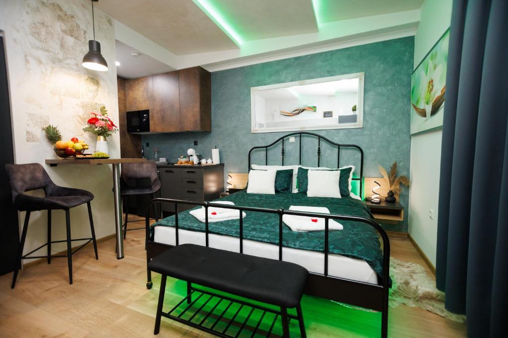 a bedroom with a bed and a table and a kitchen at Studio apartman Navis in Slavonski Brod