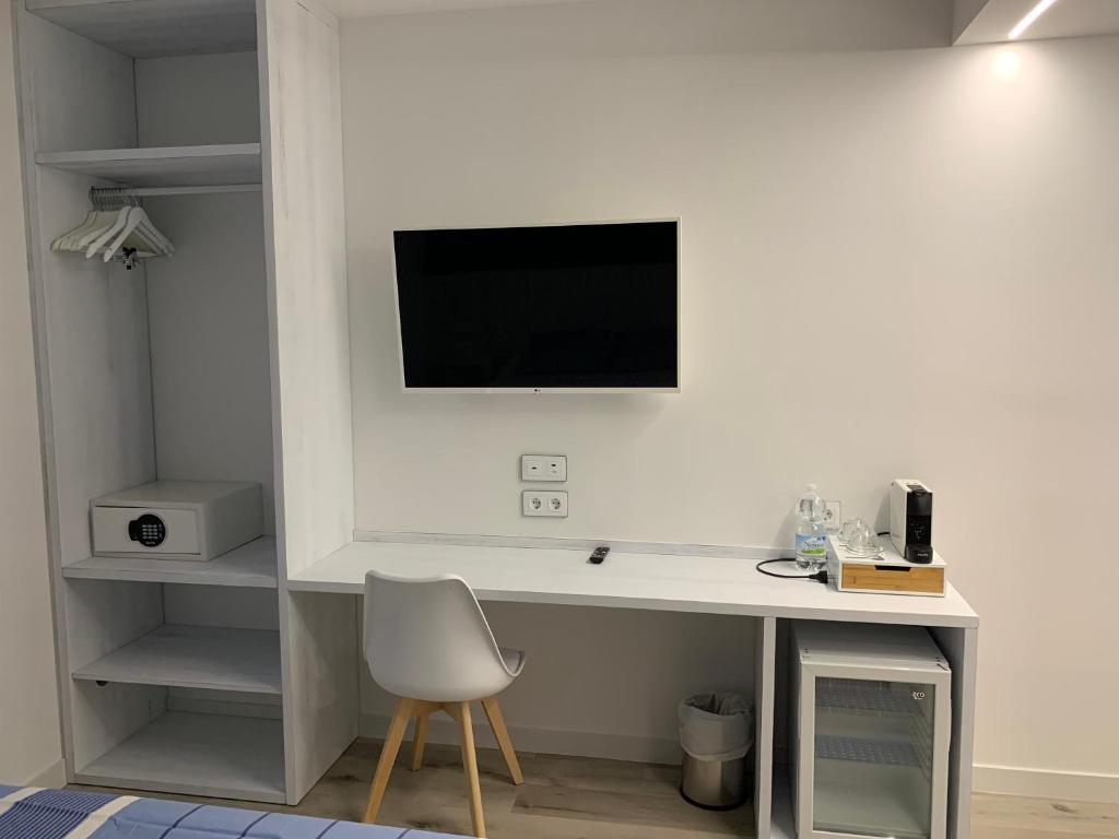 a white desk with a chair and a television on a wall at Nerja Casual Rooms in Nerja