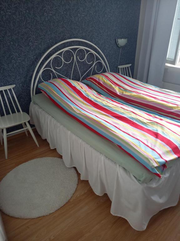 Bett mit gestreifter Decke auf einem Zimmer in der Unterkunft Citykoti in Varkaus