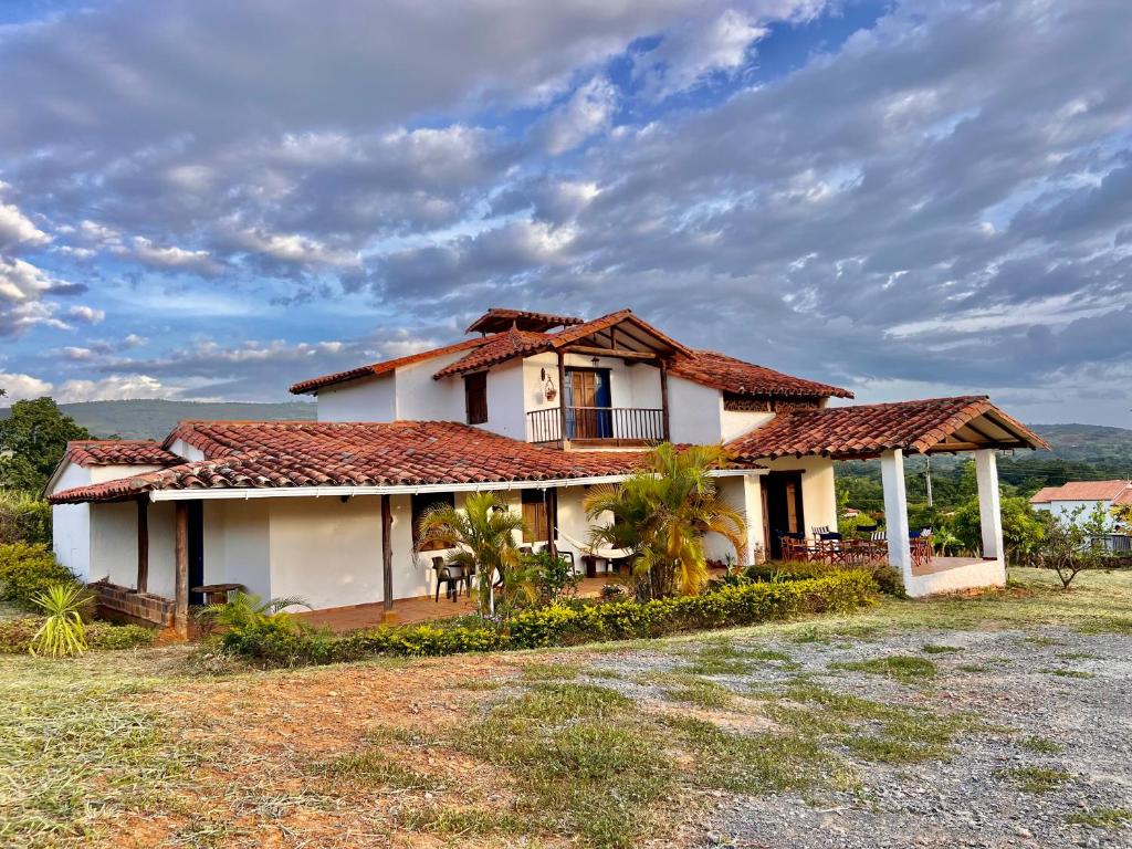 une maison blanche avec un toit rouge sur un champ dans l'établissement Casa Villa Lolita, Barichara, à Barichara