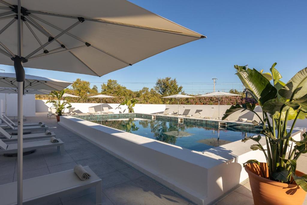 a swimming pool with an umbrella and chairs and a resort at Estudios Salinas - Fuseta in Fuzeta
