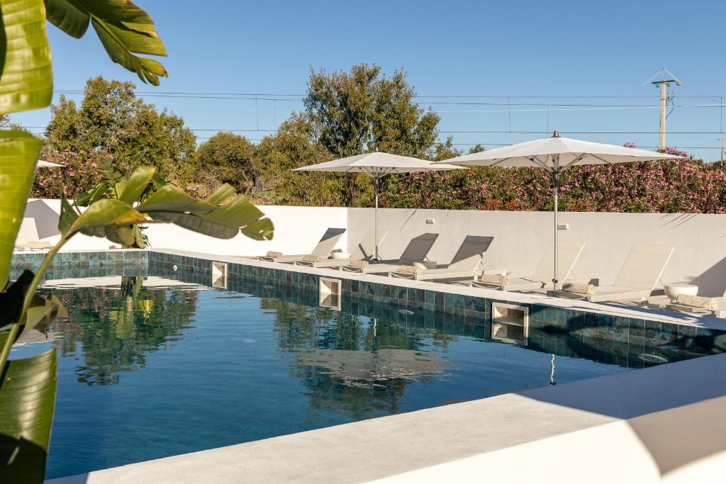 a swimming pool with lounge chairs and umbrellas at Estudios Salinas - Fuseta in Fuzeta