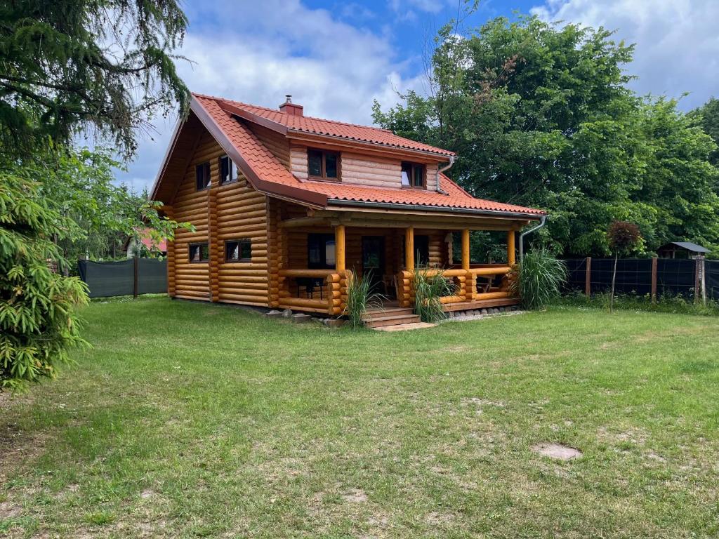 a log cabin with a red roof on a yard at Domek nad jeziorem Agnieszka i Radek Sieczkowscy in Harsz