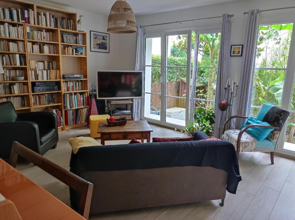 un salon avec un canapé et une télévision dans l'établissement Maison et jardin entre Paris et Disney. Idéal JO, à Rosny-sous-Bois