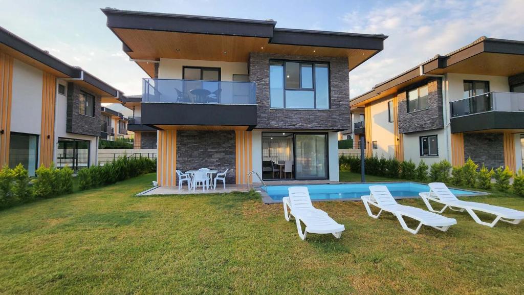 a house with a swimming pool and white lounge chairs at Villa Ala A4 Özel Havuzlu in Dalaman