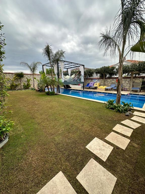 a resort yard with a swimming pool and palm trees at Grand Alaçatı Butik Hotel in Alaçatı