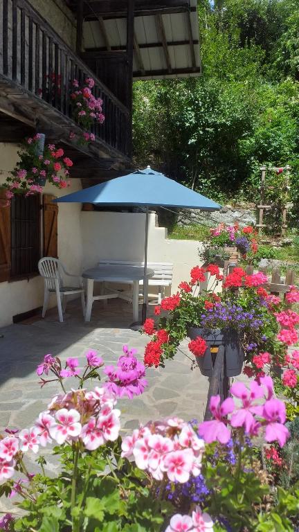 patio ze stołem, niebieskim parasolem i kwiatami w obiekcie Les VIGNEAUX Hautes Alpes, Appartement 4 personnes, avec belle terrasse panoramique w mieście Les Vigneaux