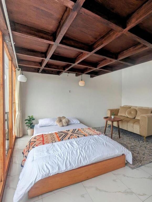 ein Schlafzimmer mit einem großen Bett und einer Couch in der Unterkunft Cottage linggayoni Dieng 2 in Diyeng