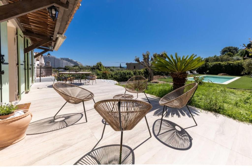 un groupe de chaises et de tables sur une terrasse dans l'établissement 06AK1 - Villa 4 bedrooms swimming pool and sauna, à Villeneuve-Loubet