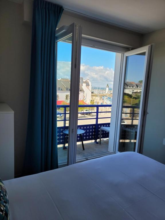 a bedroom with a bed and a balcony with a view at Hôtel Port Haliguen in Quiberon