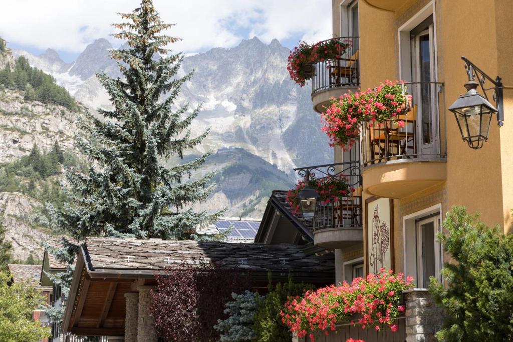 a building with flowers on balconies and a tree at Hotel Bouton d'Or - Courmayeur in Courmayeur