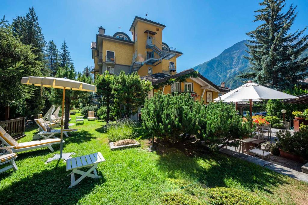 a building with a yard with chairs and umbrellas at Hotel Bouton d'Or - Courmayeur in Courmayeur