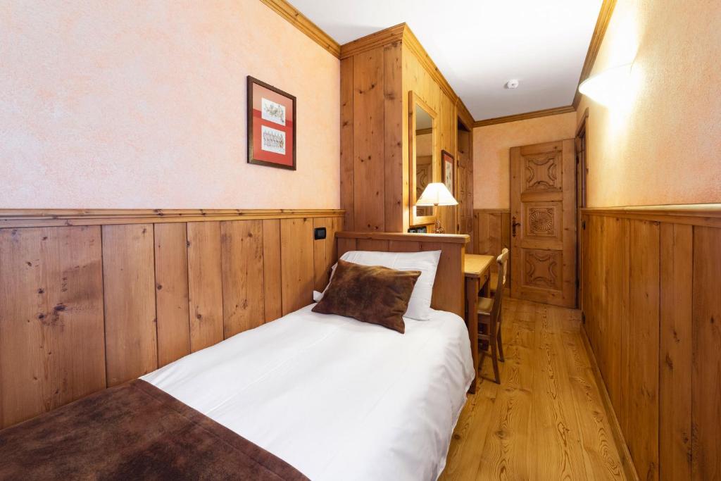 a bedroom with a bed with wooden walls and a table at Hotel Bouton d'Or - Courmayeur in Courmayeur