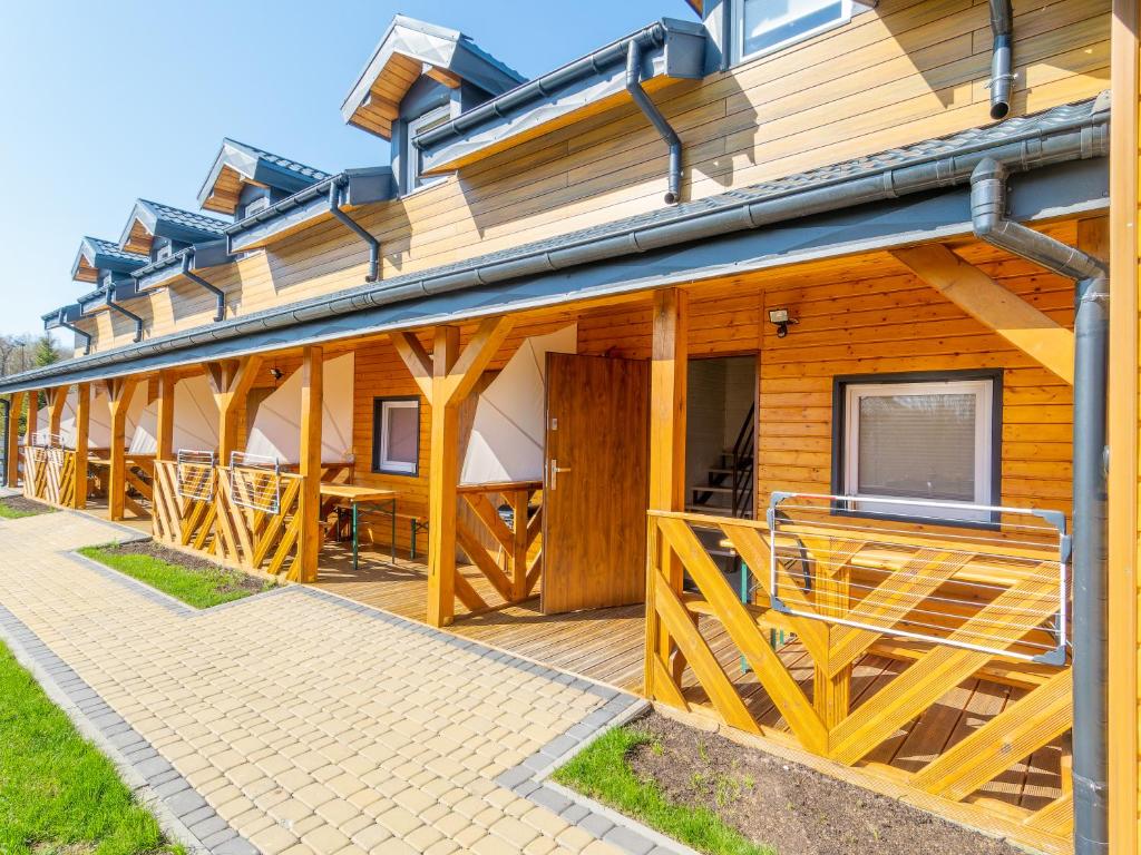 une maison en bois avec un porche et une terrasse dans l'établissement Domki Drewniane TREBOR, à Międzyzdroje