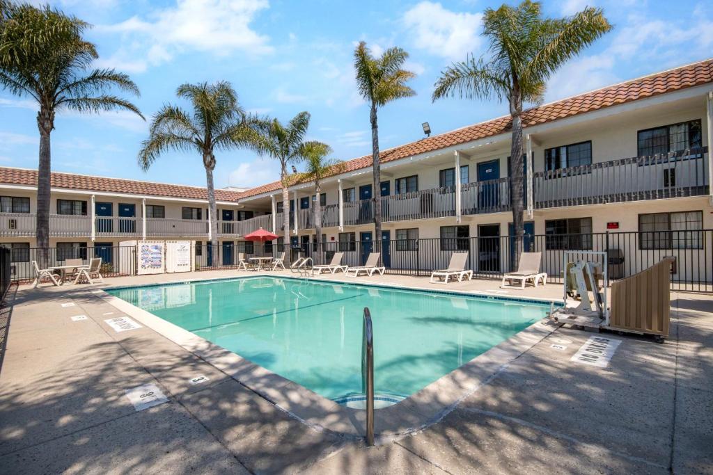 a swimming pool in front of a building with palm trees at Motel 6-Lompoc, CA in Lompoc