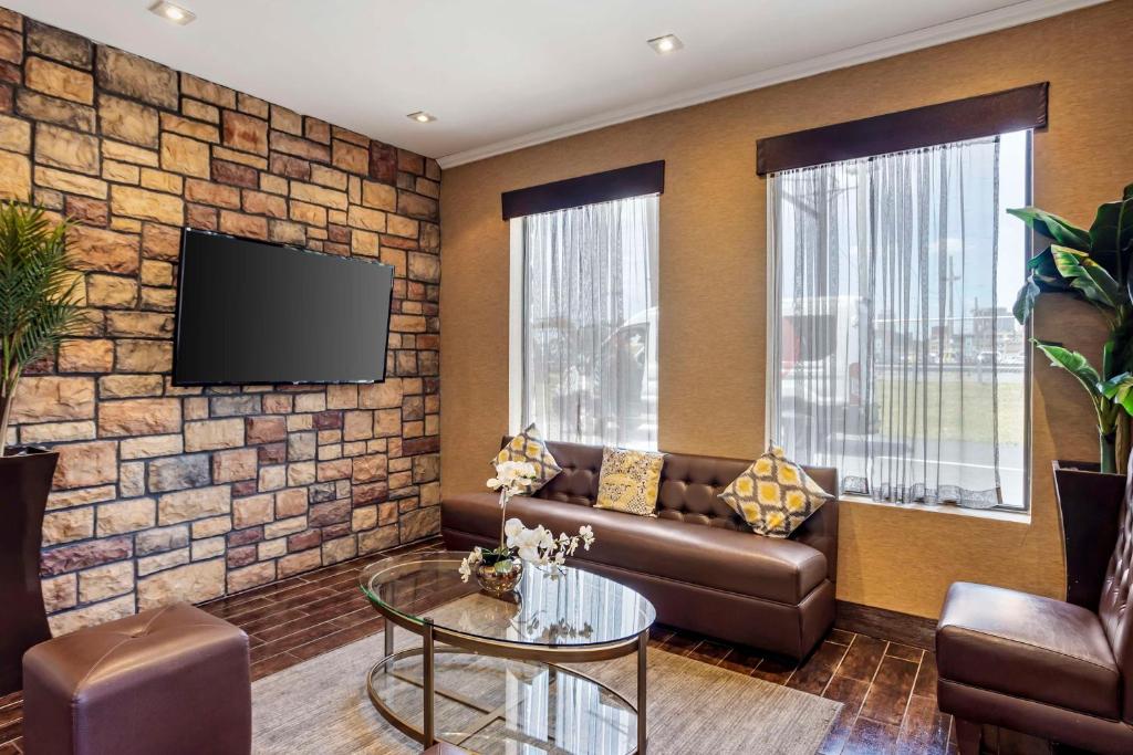 a living room with a couch and a tv on a brick wall at Best Western Plus Newark Airport West in Newark