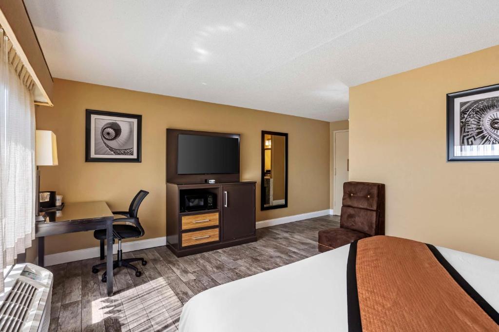 a hotel room with a bed and a desk and a television at Best Western Plus Newark Airport West in Newark
