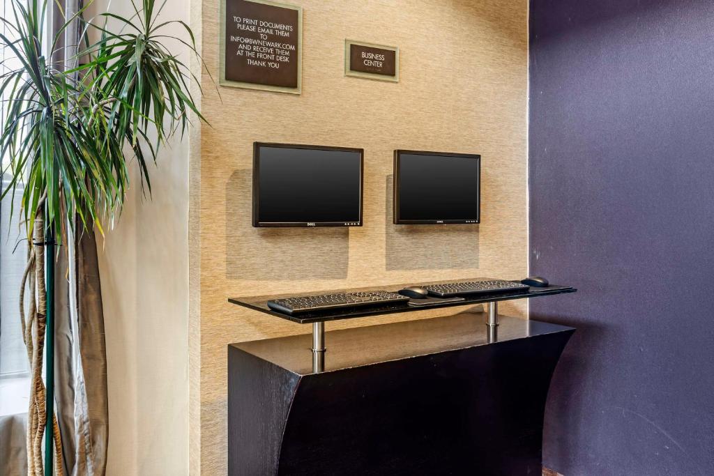two computer monitors on a wall with two keyboards at Best Western Plus Newark Airport West in Newark