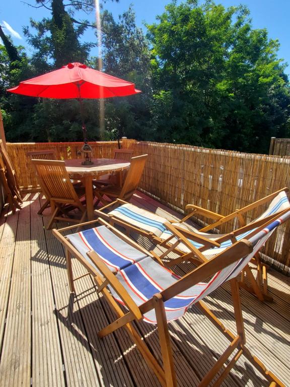 une table et des chaises avec un parasol sur une terrasse dans l'établissement Jolie maison en bois à 600m de la plage des Vergnes, à Meschers-sur-Gironde