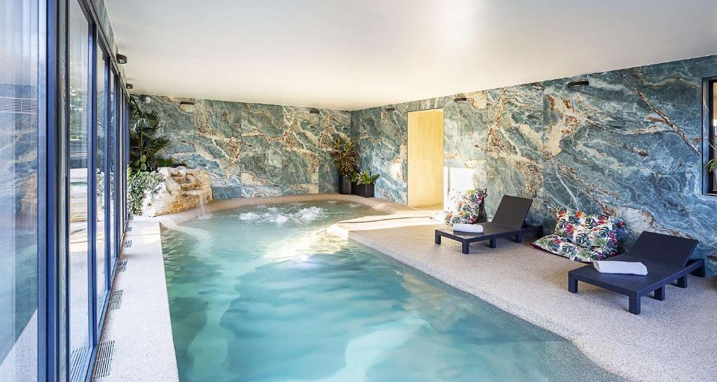 Una piscina en medio de una habitación con una pared de roca. en Best Western Amarys Hotel &amp; Spa, en Rambouillet