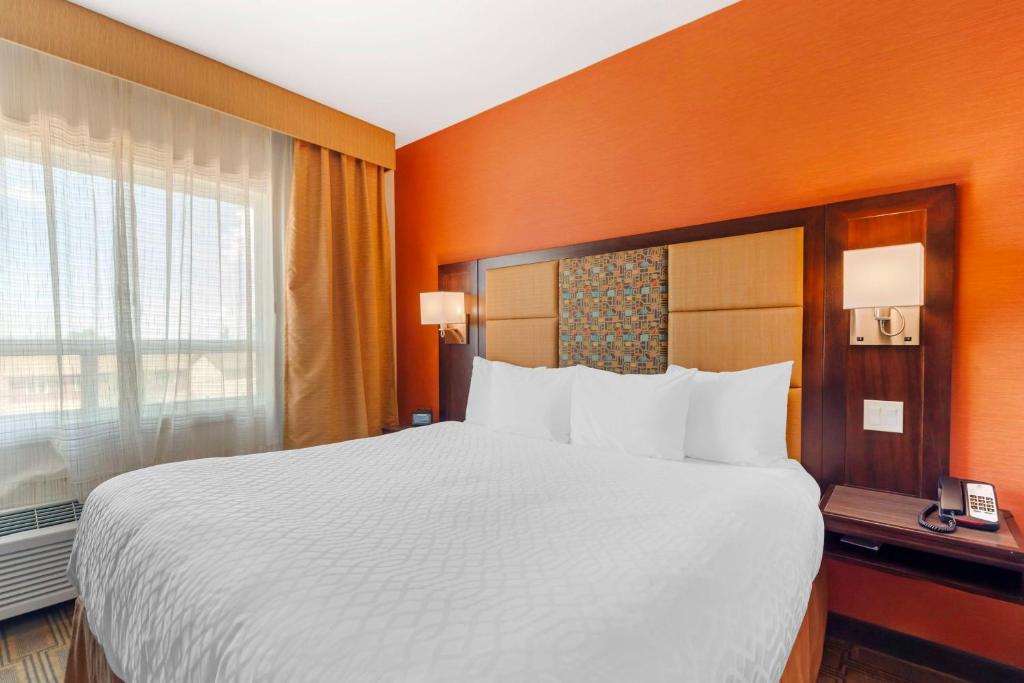 a hotel room with a large bed and a window at Best Western Plus Chateau Fort St. John in Fort Saint John
