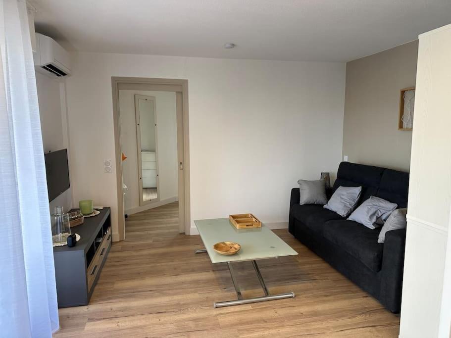 un salon avec un canapé noir et une table dans l'établissement Studio cabine en étage, front de mer, à Fréjus