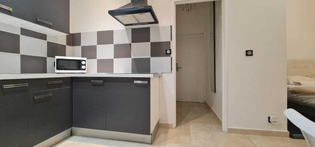 une cuisine avec un mur en damier noir et blanc dans l'établissement Appartement de la Richelandiere, à Saint-Étienne