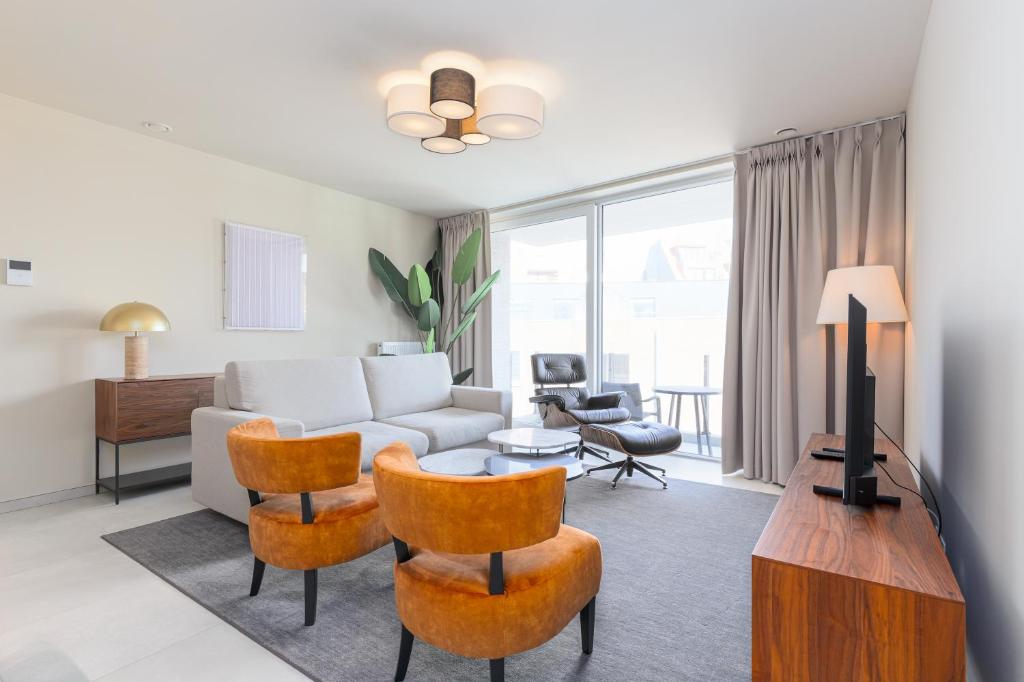 een woonkamer met een bank en een tafel bij Leader De Haan - Casselbergh Residences in De Haan