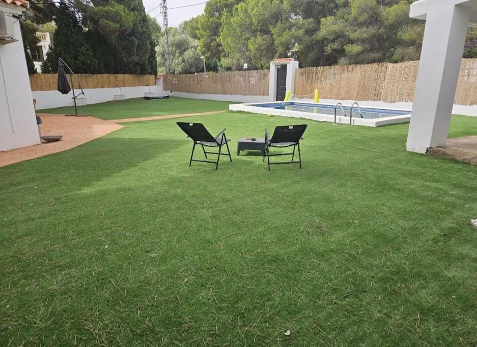 two chairs sitting in the grass near a swimming pool at La Cañada in Partida de La Cañada