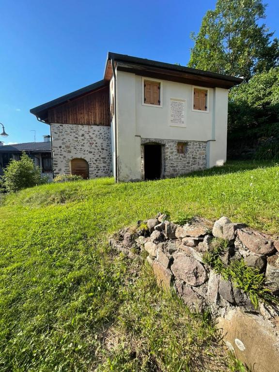 a building on a hill with a stone wall at Casa Rita, Altopiano di Piné Ospitar in Pergine Valsugana
