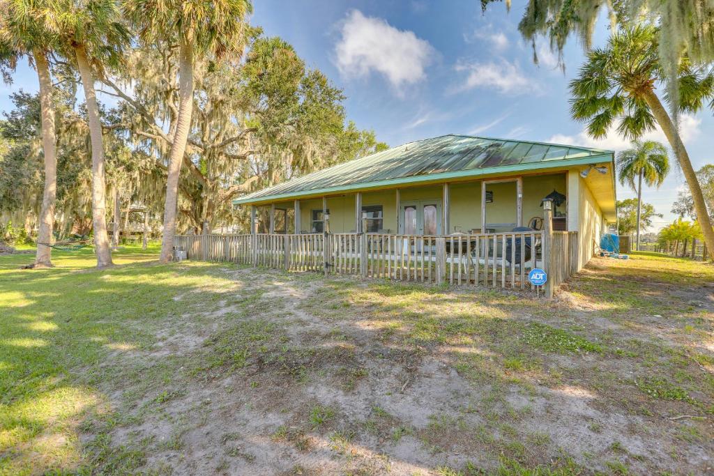 a yellow house with a fence and palm trees at On Lake Istokpoga Lorida Home with Lanai! in Sebring