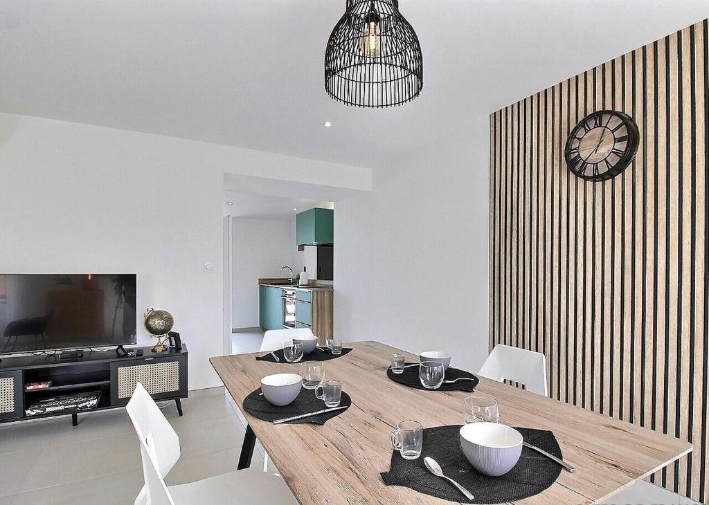 une salle à manger avec une table, des chaises et une horloge dans l'établissement Gîte Louise entre Erquy et Fréhel 2 chambres, à Plurien