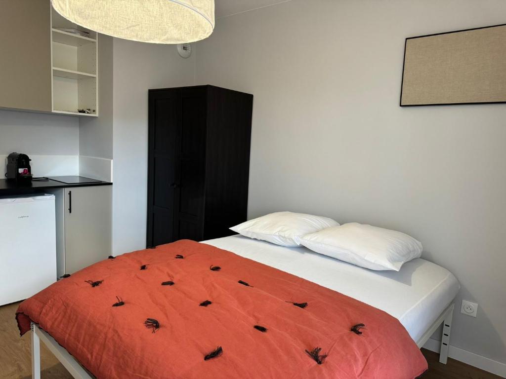- une chambre avec un lit et une couverture orange dans l'établissement M73 Marquer joli studio centre ville d'Annemasse, à Annemasse