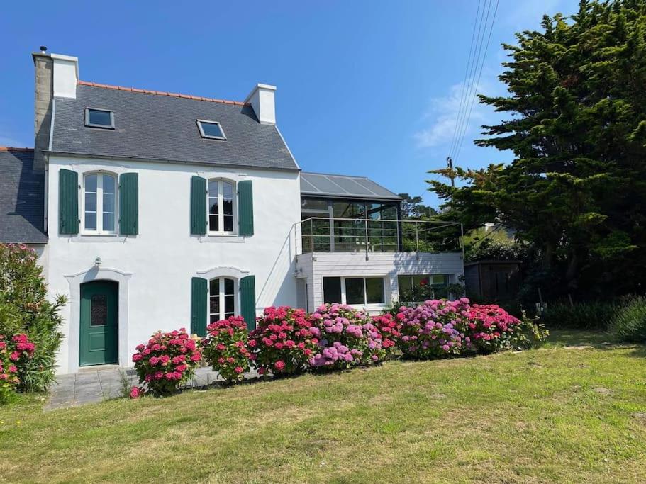 une maison blanche avec des fleurs roses dans la cour dans l'établissement Maison avec vue mer et accès plage à Plougasnou, à Plougasnou