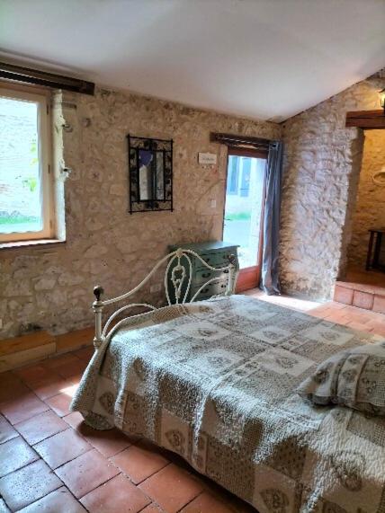 une chambre avec un lit dans un mur de pierre dans l'établissement Chambre d'hôtes en Dordogne proche Eymet, à Fonroque