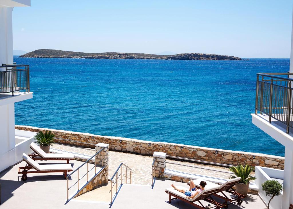 a couple sitting in chairs on a balcony overlooking the ocean at Blue Sea Paros Aegean Horizon in Drios