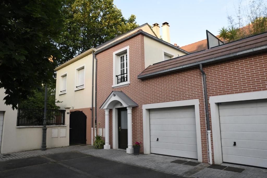 アニエール・シュル・セーヌにあるLe Clos Ménilの通り二面のガレージドアがあるレンガ造りの家