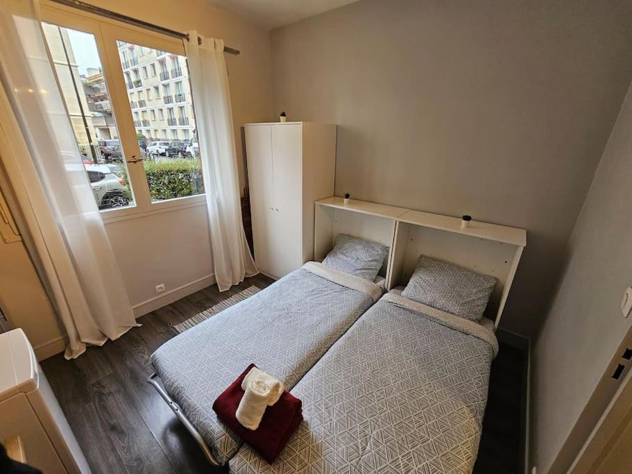 une chambre avec deux lits et une fenêtre dans l'établissement Meilleur emplacement au meilleur budget, idéal pour un séjour de plus d'un mois à Boulogne-Billancourt et Paris 16, à Boulogne-Billancourt