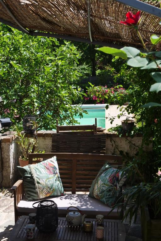 un banc en bois avec deux coussins assis sous une pergola dans l'établissement Le Nid du Cormier, à Ville-Saint-Jacques