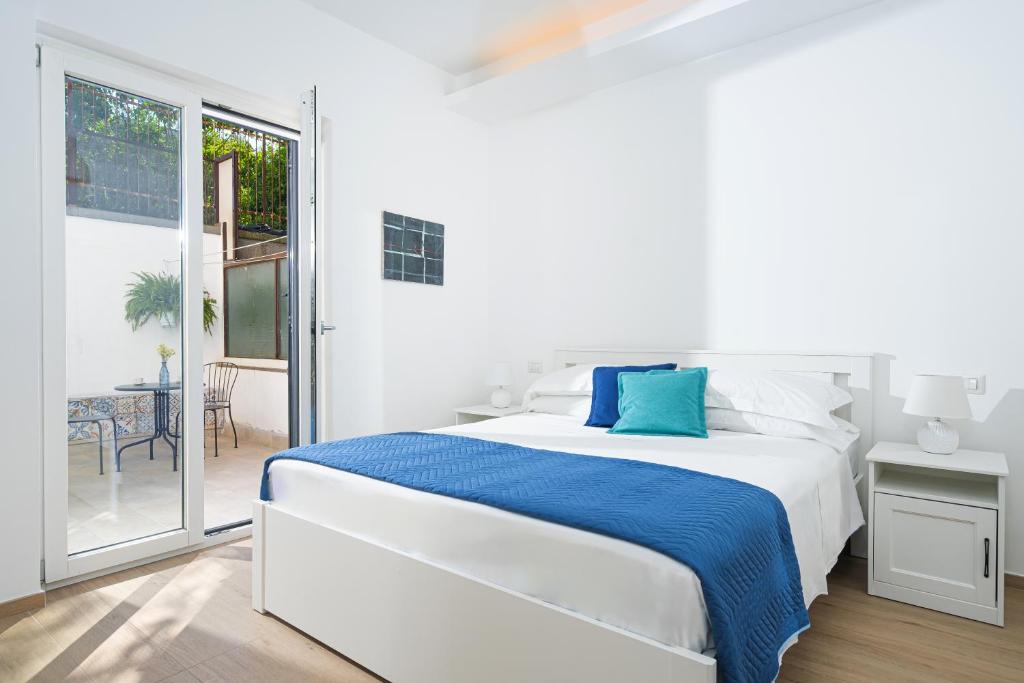 a white bedroom with a bed and a balcony at Casa Stella in Vico Equense