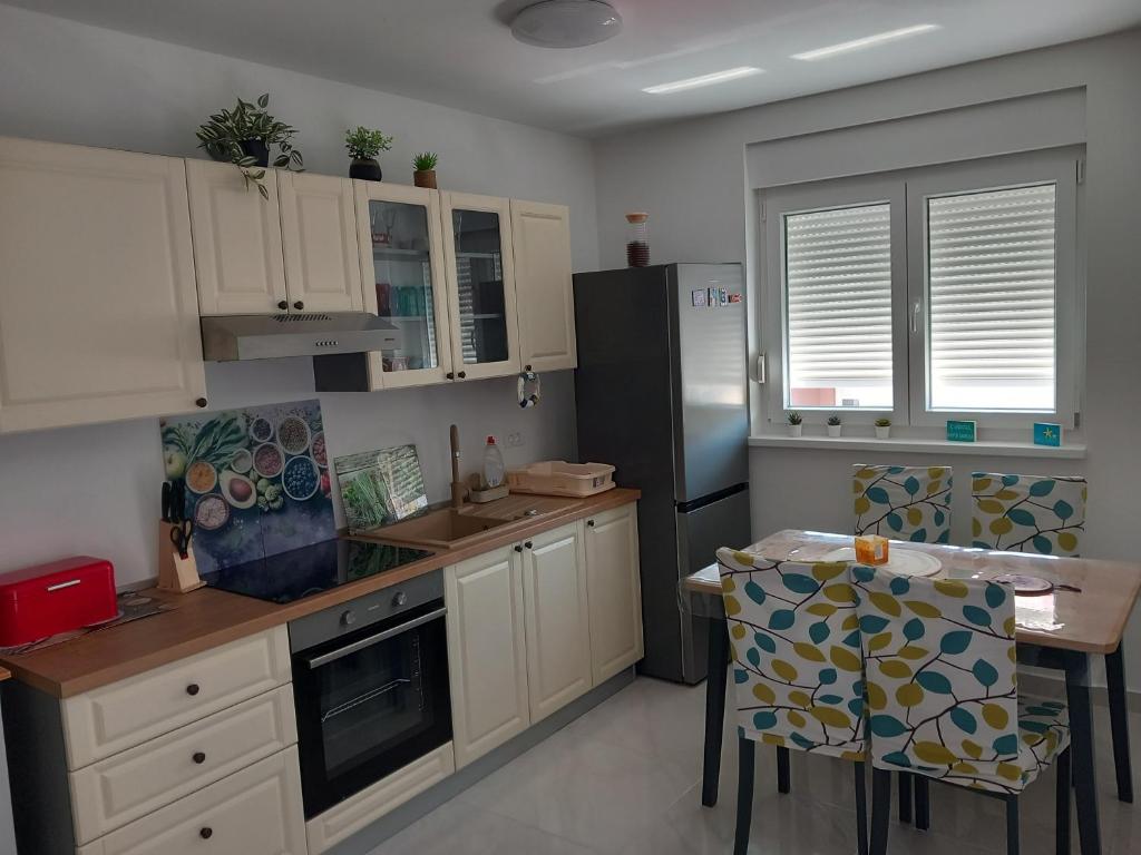 a kitchen with white cabinets and a black refrigerator at Apartman Dina in Peroj